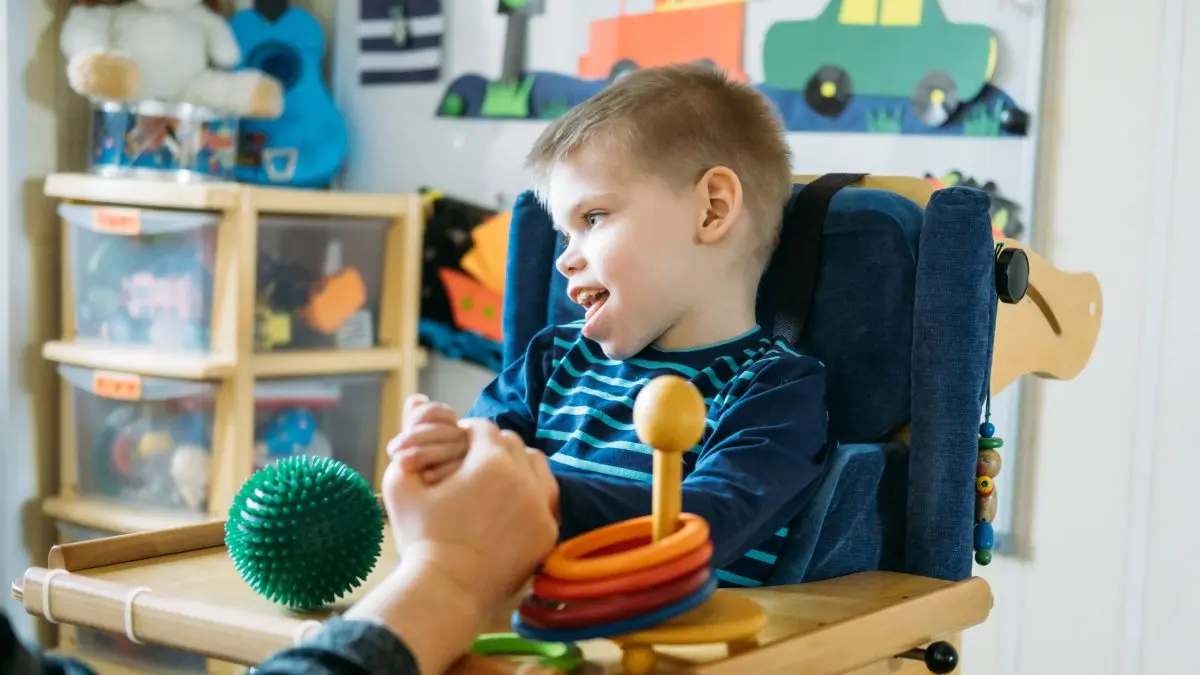 Bambino con paralisi cerebrale su un seggiolone.